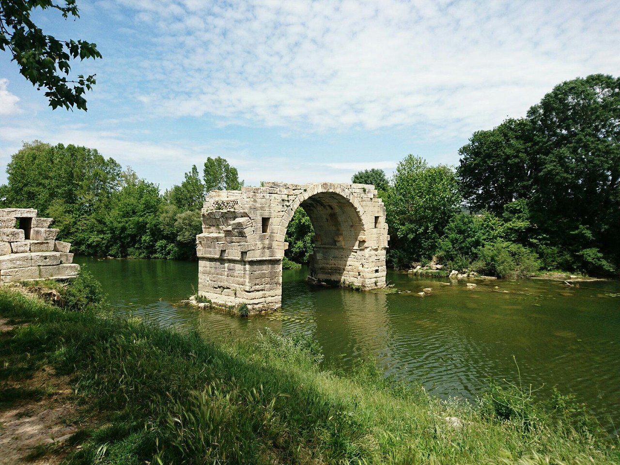 Vestiges d’un pont en pierre au-dessus d’une rivière, environnement verdoyant