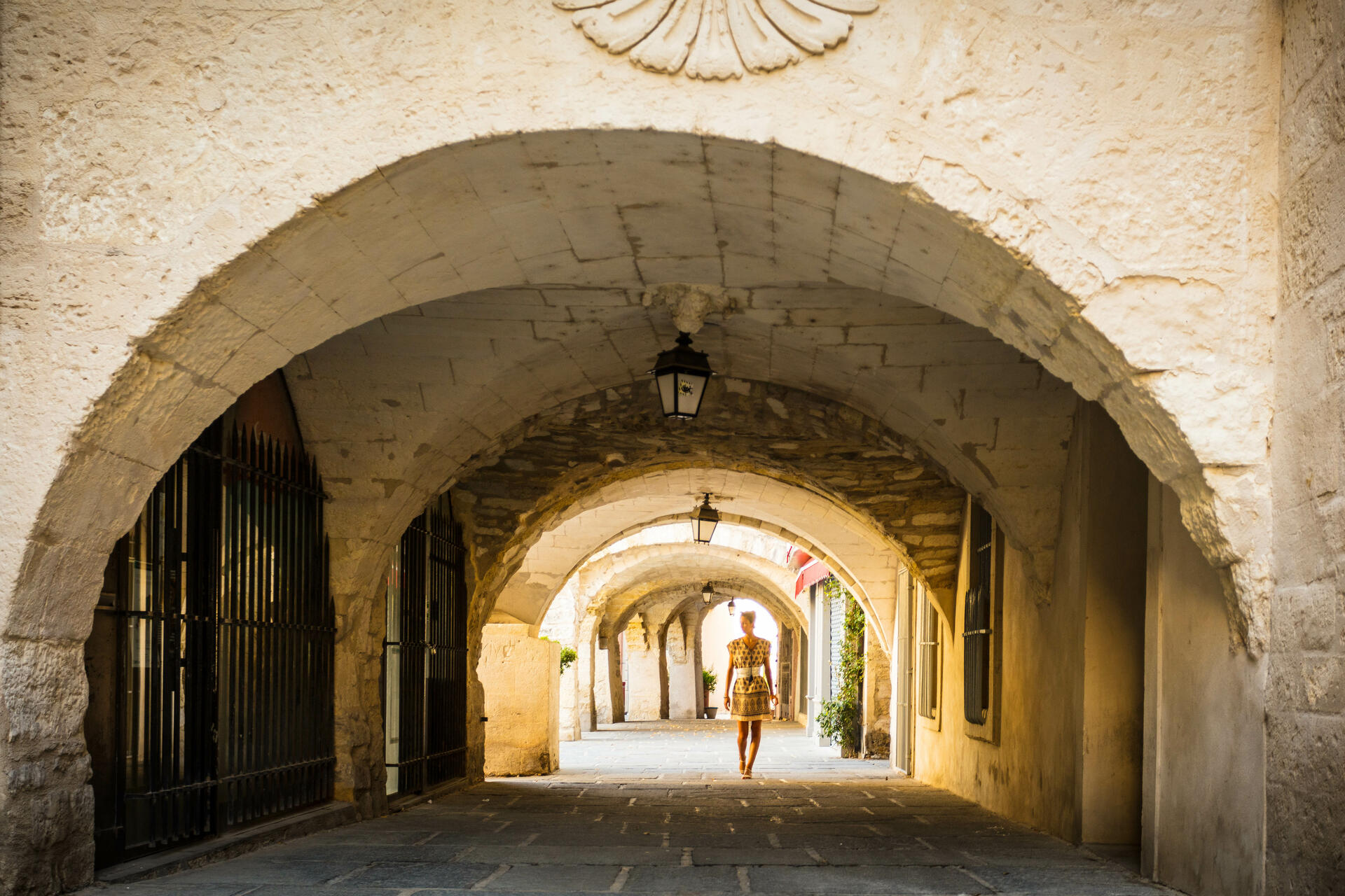 Passage voûté en pierre avec une personne marchant au centre, ambiance de ruelle ancienne